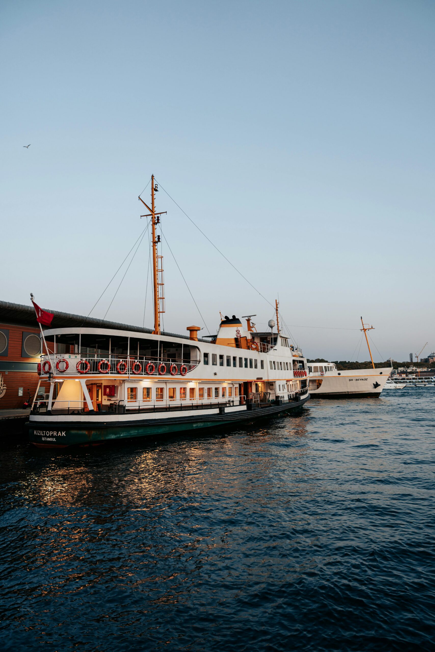 Two vintage ferries anchored at a serene harbor during sunset, capturing a tranquil maritime scene.