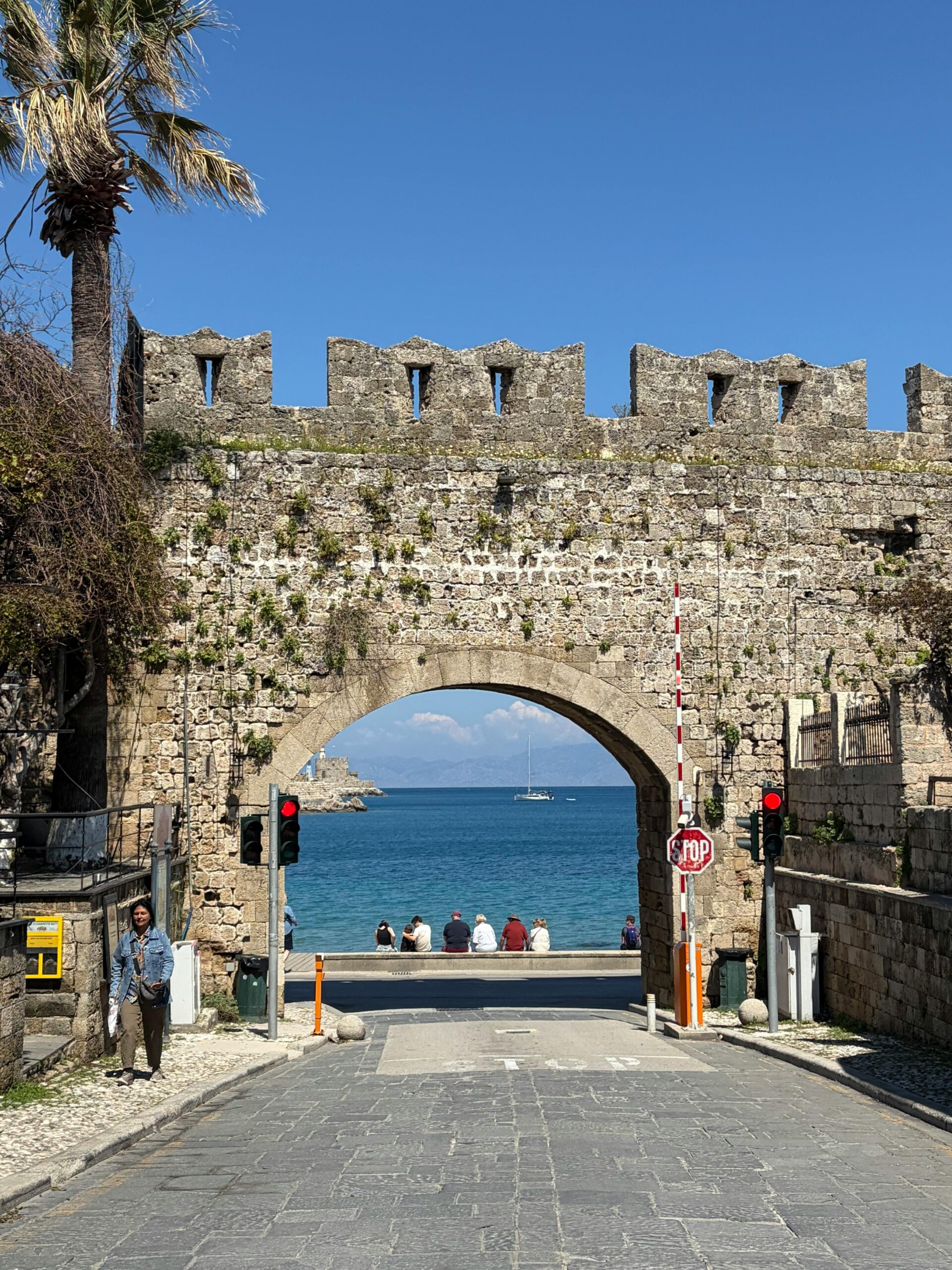 Stone medieval gate leading to scenic view of the Aegean Sea in Rhodes, Greece.